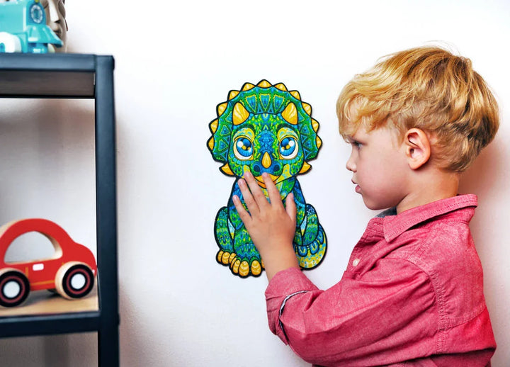 Kind spielt mit bunter Dinosaurier-Wanddekoration im Kinderzimmer neben Spielzeugauto